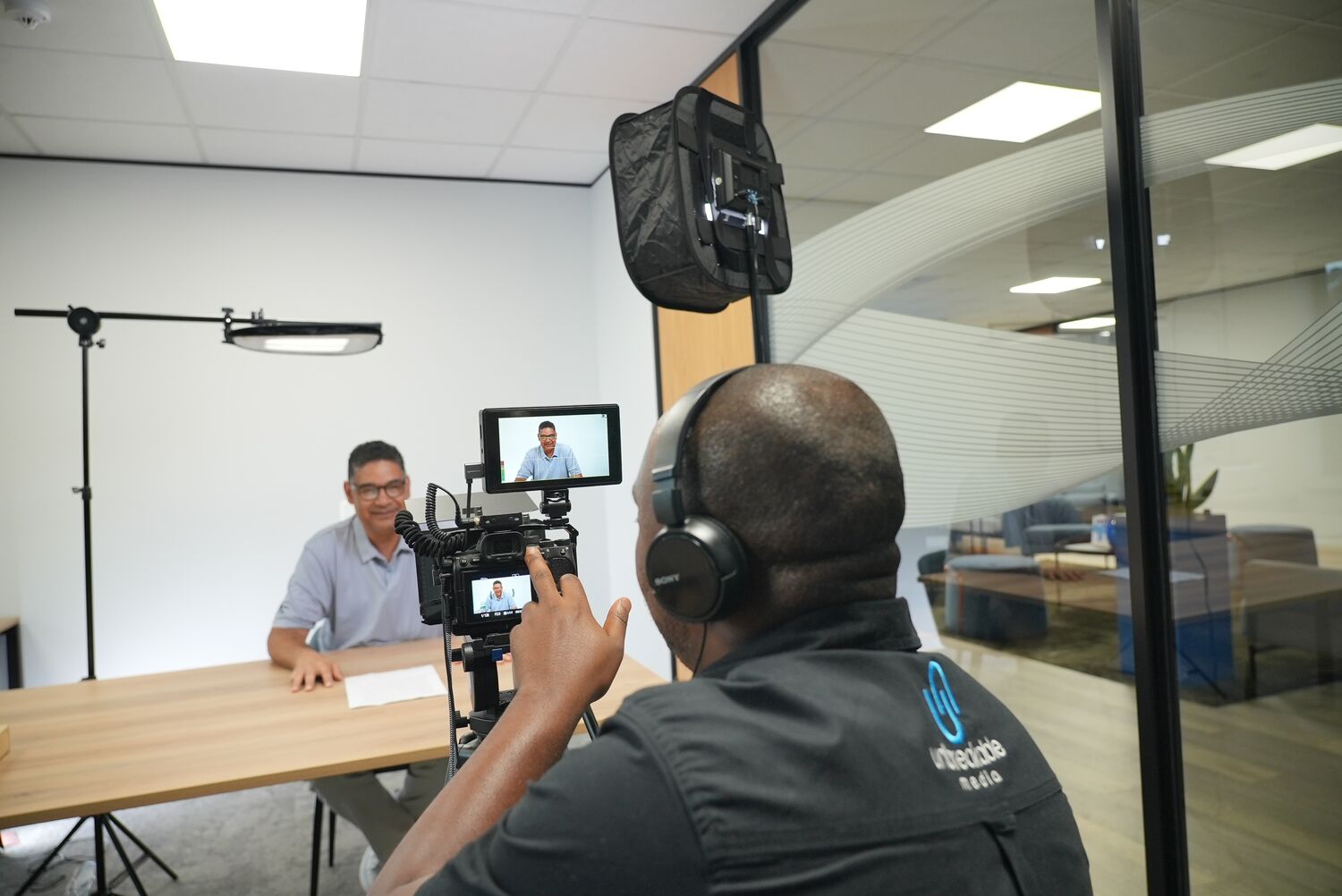 A camera operator filming an employee interview with an on-camera monitor