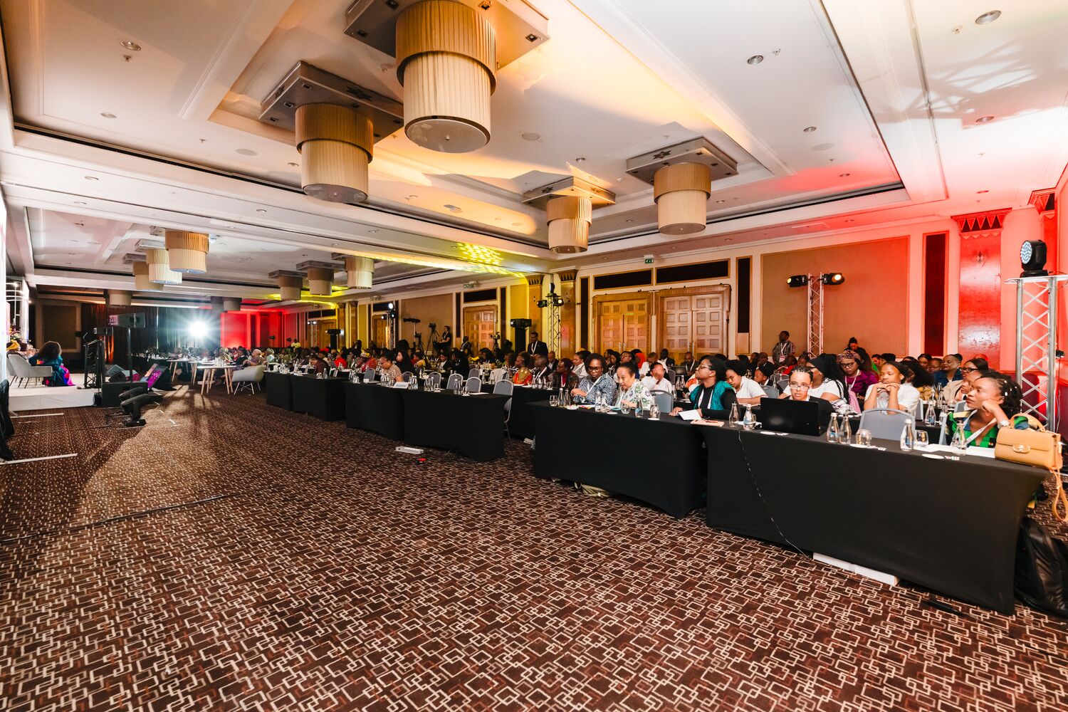 Wide shot of delegates seated in the summit ballroom