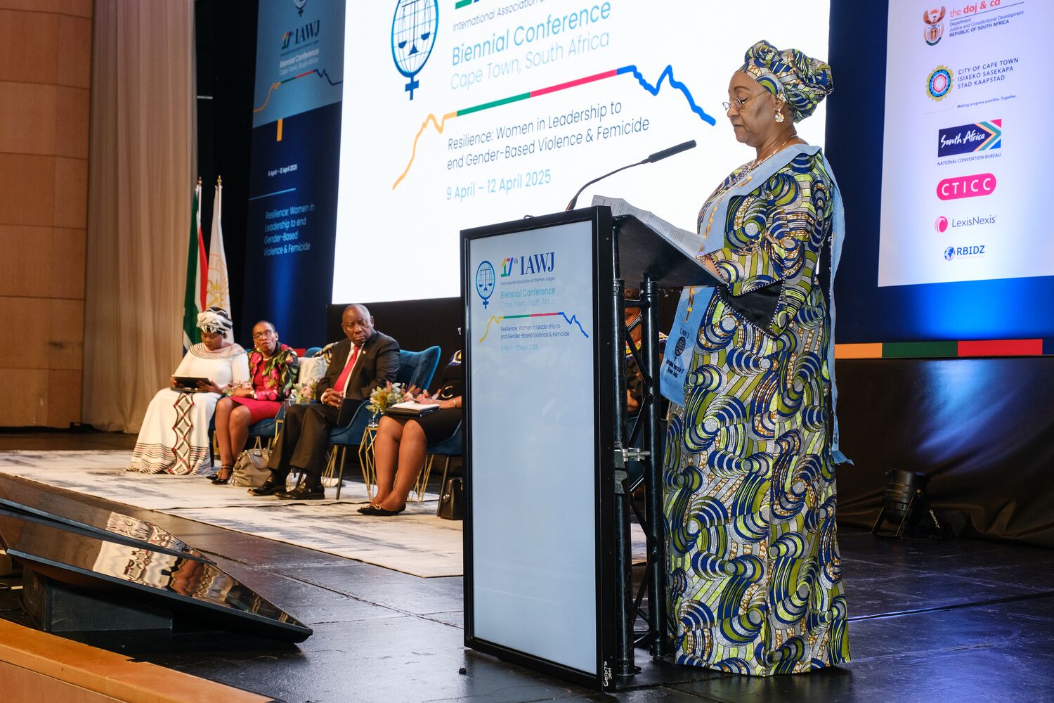 A delegate addressing the conference from the podium beneath the event branding