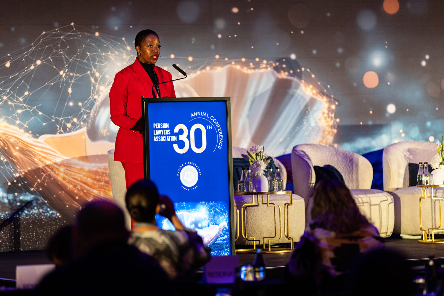 A speaker at the podium beside the 30th anniversary branding