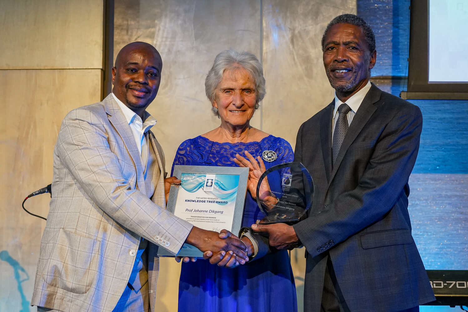An award being presented on stage at the symposium