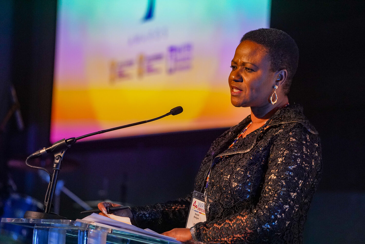 A speaker at the podium against a colourful stage backdrop