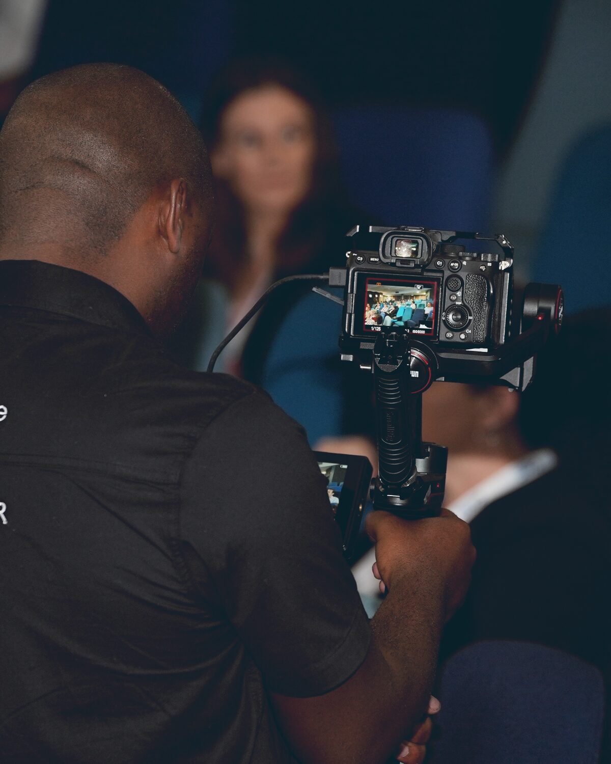 Videographer capturing delegate reactions from within a seated conference audience