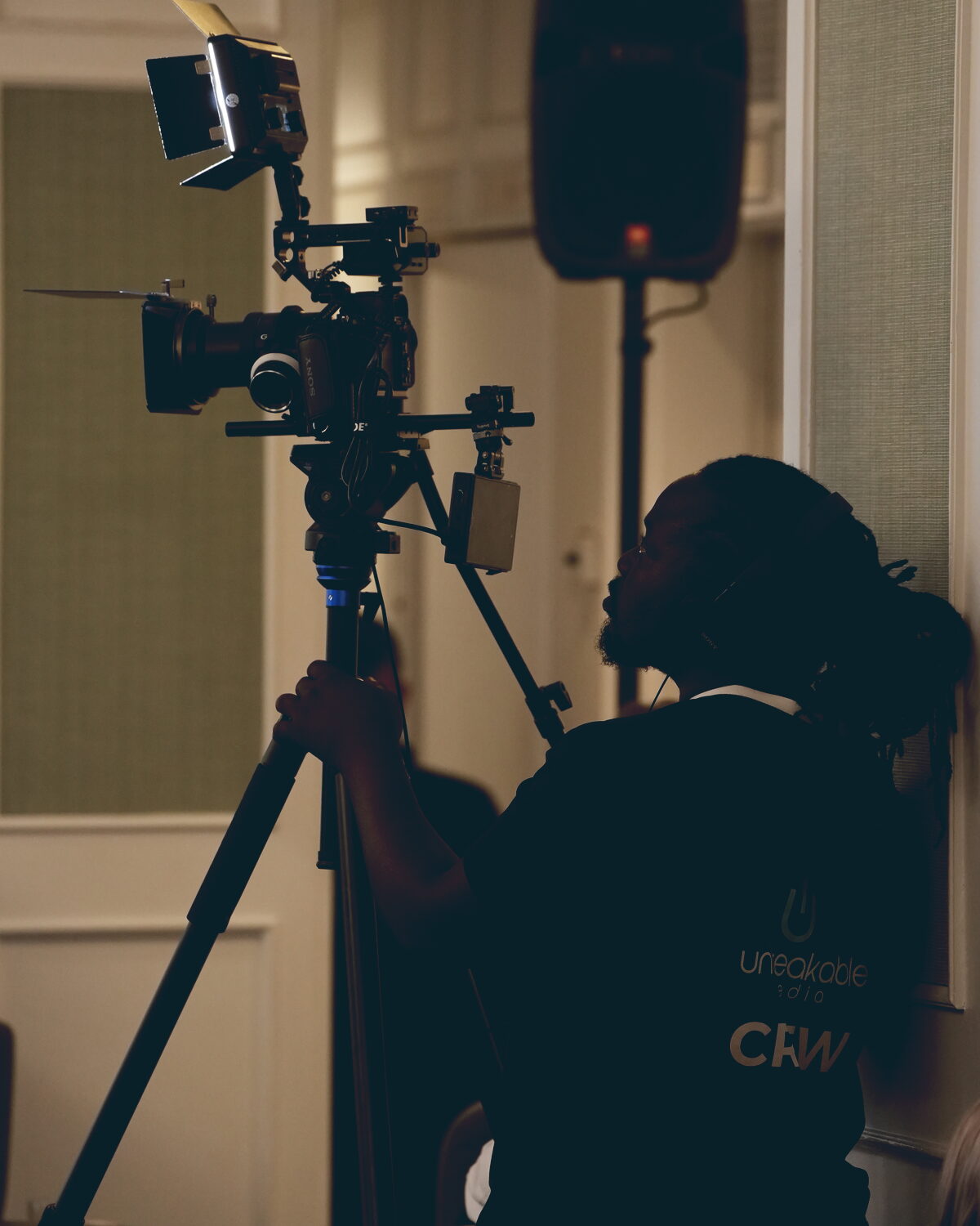 Camera operator filming a conference session on a rigged cinema camera with top light