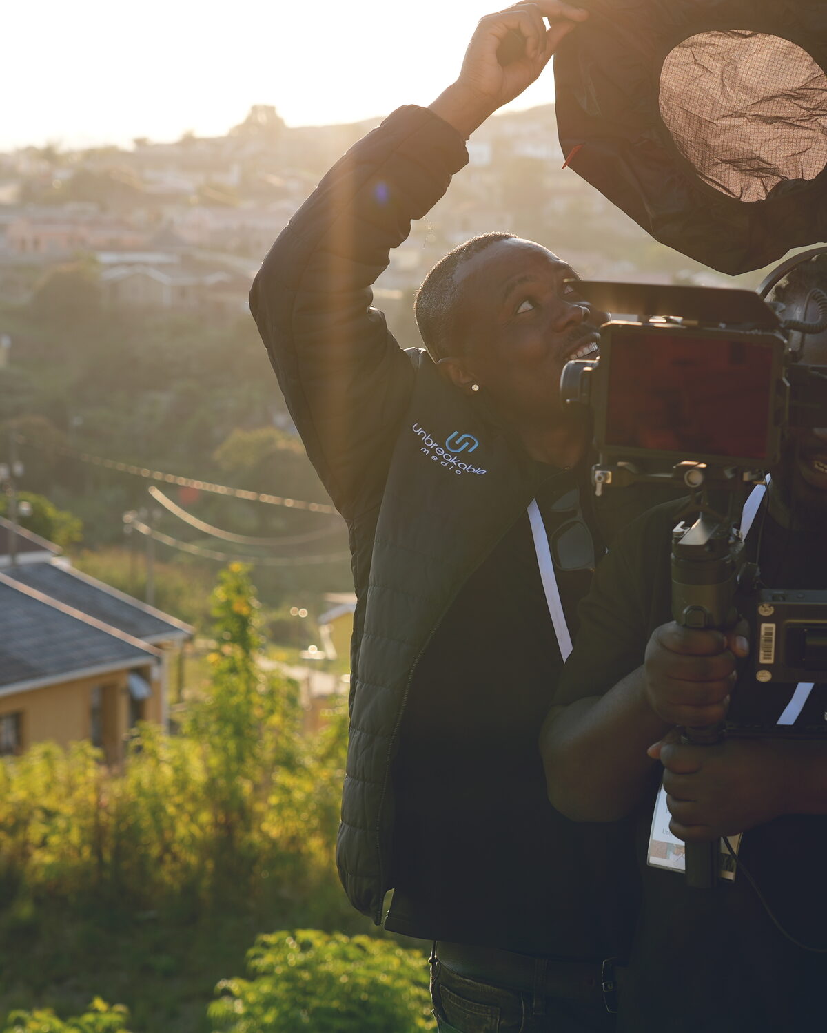 Videographer lining up a shot outdoors in golden-hour light