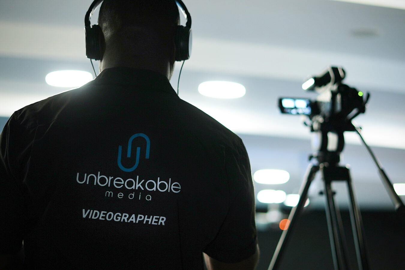 Camera operator filming behind a tripod-mounted camera